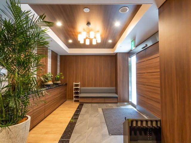 温かみのあるエントランス エントランス 広々としたスペースとナチュラルな木目調が落ち着きを醸し出しています。植物が心地よいアクセントとなっています。