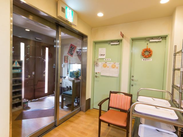 エントランスの掲示物と装飾 エントランス ガラス扉越しに見える温かみのある入り口は、訪れる方々を暖かく迎え入れます。玄関には季節感のある装飾が施され、明るい雰囲気が漂っています。
