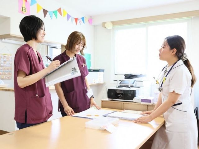 職員の打ち合わせ室 多目的室   明るい空間で職員同士が打ち合わせをしています。書類を広げやすい大きな机があり、連携しやすい雰囲気です。