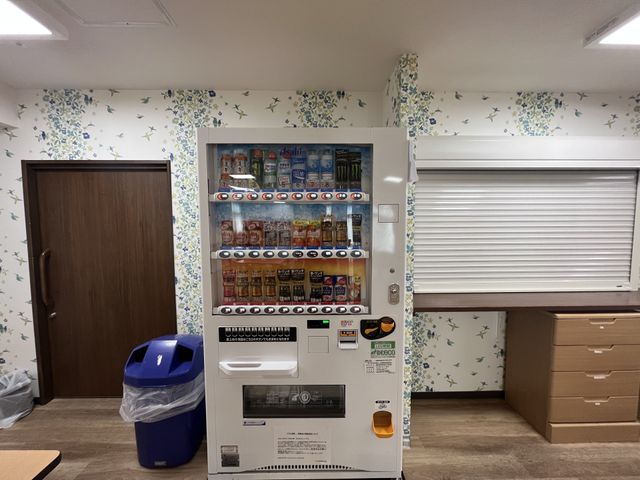 自販機とゴミ箱のある部屋 休憩室 壁紙で彩られたリラックスできる空間です。休憩中に飲み物を購入できる便利な設備があります。
