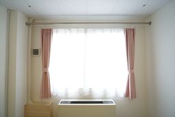 明るい窓とエアコンのある室内