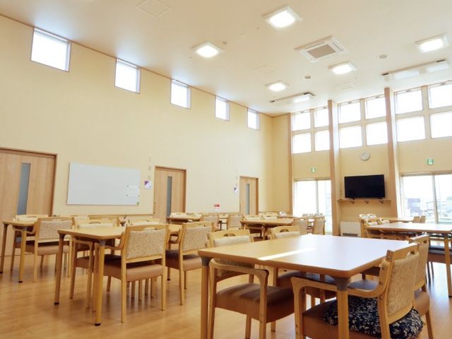 明るい食堂 食堂   高い天井と大きな窓で、開放感のある食堂です。ゆったり配置されたテーブル席があり、落ち着いて過ごしやすい雰囲気です。