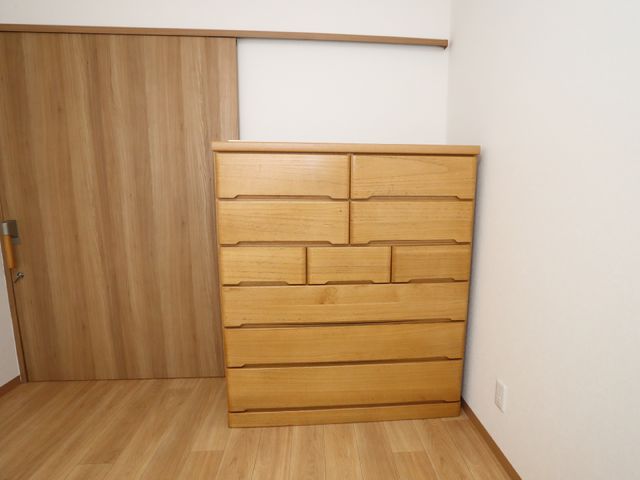 木製の洋服箪笥とドア 居室 すっきりとしたデザインの居室には、収納力のある木製の箪笥が備え付けられており、快適な生活空間を支えます。