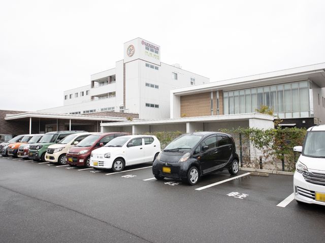 白い建物と駐車場外観 外観 清潔感のある外観と整備された駐車場が広がっており、ご来訪の際にも安心してお車を停められます。