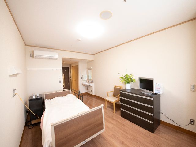 快適な居室空間 居室 落ち着いた色合いのベッド周りと広々とした部屋が特徴です。個室でのんびりとお過ごしいただけます。