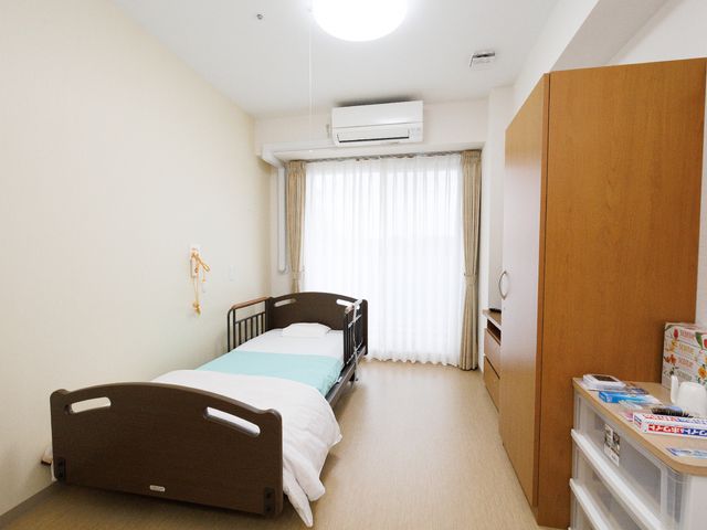 居室のベッドと家具 居室 広々とした清潔な個室で、快適な私空間をお過ごしいただけます。窓からは自然光が差し込み、明るく穏やかな雰囲気です。