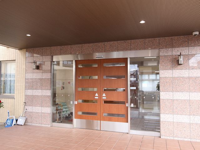 入口の木製ガラス扉 玄関 心地よい光が差し込むエントランスは、訪れる方々を温かく迎え入れます。きれいに保たれた入口周りが、安心感を与えてくれます。