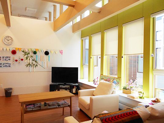 大きな窓が付いたリビングにはソファやテレビがあり、壁には笹飾りが飾られている。