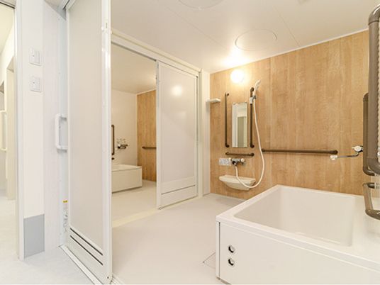 個浴室が二つ並んで設置されていて、行き来ができるようになっている。それぞれブラウンの手すりが壁に付いている。