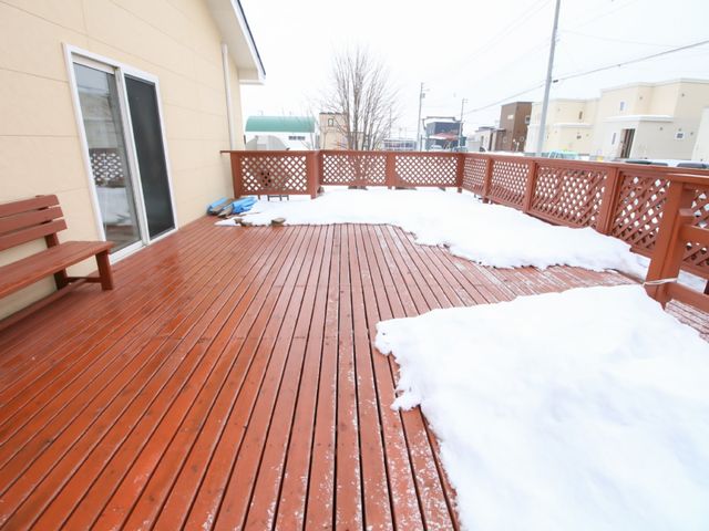 雪の積もった木製テラス テラス 雪景色を望むウッドデッキで、四季の移ろいを感じながらリラックスしたひとときを過ごせます。温かみのある木目調が印象的です。