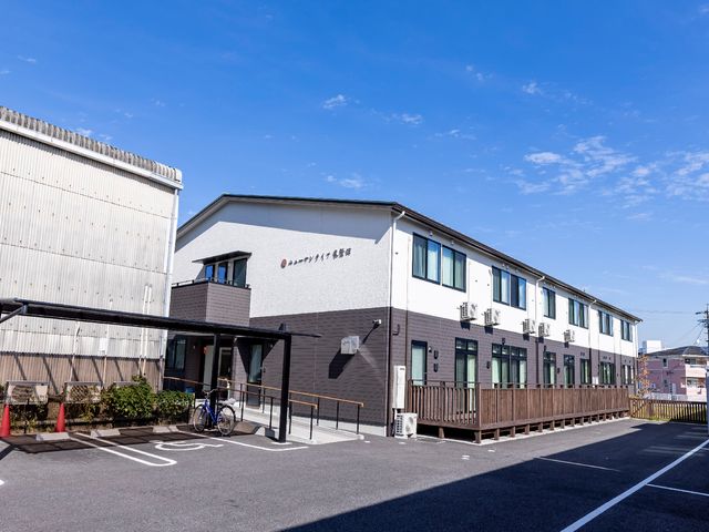白壁の建物と青空 外観 広々とした駐車場を持つ明るい建物です。外からも清潔感が伝わり、快適な職場環境をご提供いたします。