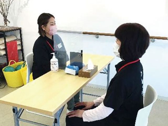 対面座りの二人 内観 明るい場所でマスクを付けた職員同士が向かい合い、対話を楽しめる空間です。