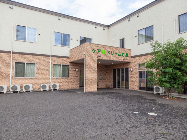 清潔感ある施設のエントランス 外観 緑豊かな入口が迎える落ち着いた雰囲気の場所です。働くスタッフの快適な環境が整っています。