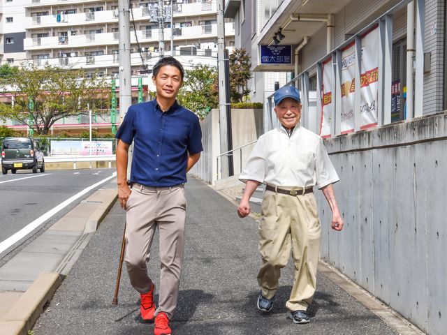 散歩する二人の人物 笑顔で一緒に歩くスタッフと利用者の姿が、心地よいコミュニケーションの場を物語っています。ここでは支え合いながら、日々の活動を楽しむ様子が窺えます。
