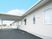 平屋建ての建物の外壁は白で清潔感がある。玄関先には大きな車寄せが設置されている。