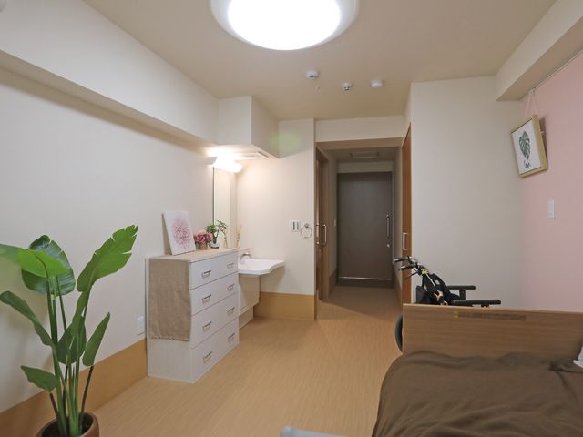快適な個室居室 居室 落ち着いた色合いの居室で、リラックスしながら過ごせる空間が整っています。壁に掛けられたアートや植物が、暮らしに彩りを添えています。