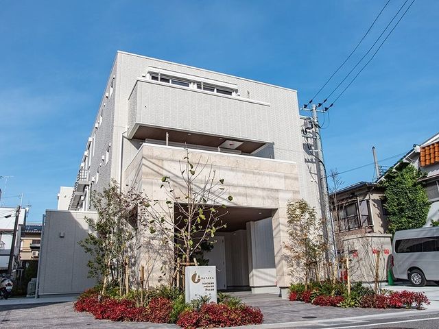 モダンな建物のエントランス 外観 清潔感のある外観で、暖かい日差しが降り注ぐエントランスが迎えてくれます。周囲の緑が彩りを添え、心地よい空間を演出しています。
