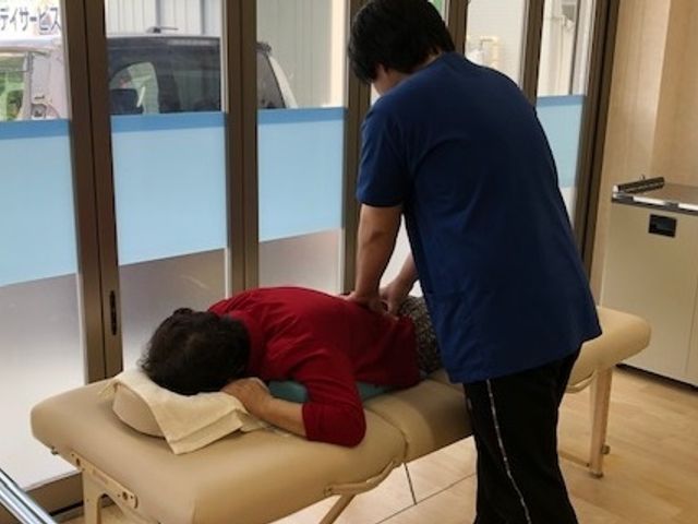 窓際で施術中の室内 機能訓練室 窓から自然光が入る明るい空間で、利用者がリラックスしながら施術を受けています。快適な職場環境です。
