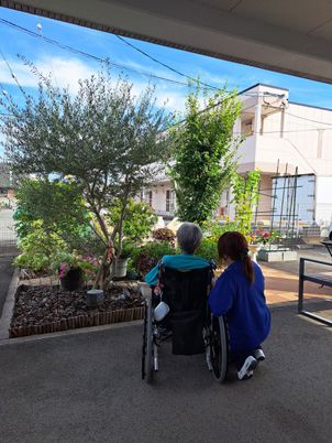 車椅子と職員が庭先にいる中庭  
