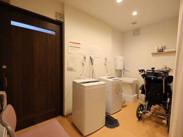 洗濯設備と車椅子 脱衣所 きちんと整理された洗濯室で、自立した日常生活をサポートします。車椅子ユーザーも利用しやすい配置です。