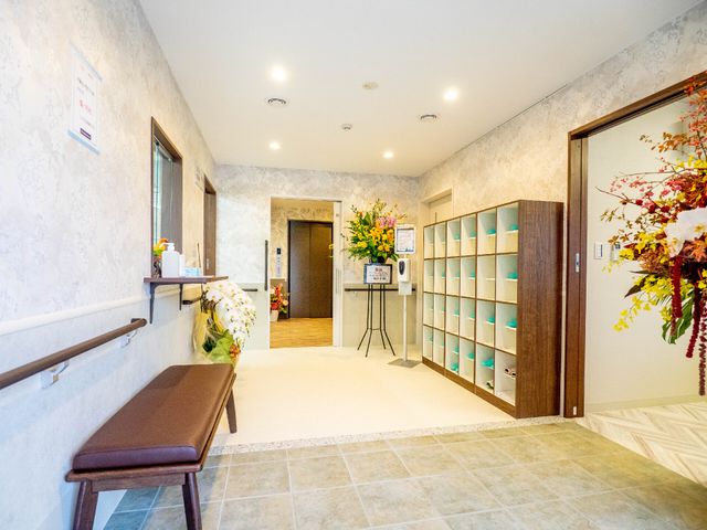 エントランスの明るい廊下 玄関 手すりが備わった広々とした入口周りは、花々が彩る心地よい空間を演出してくれています。お仕事を通じて、このような癒しの環境を提供するお手伝いができます。