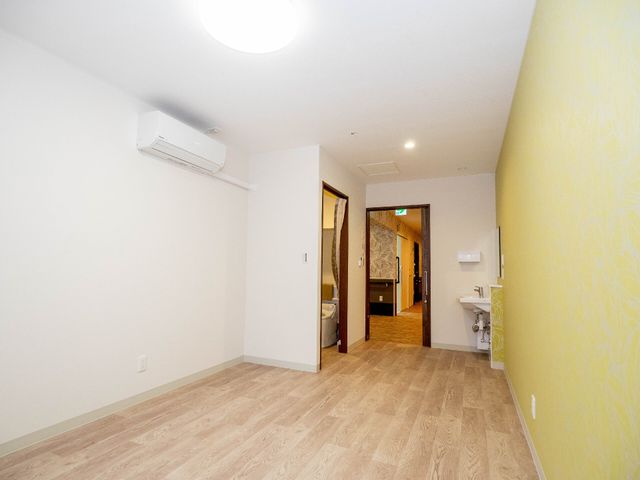 広々とした洋室の一角 居室（トイレあり） ゆったりと配置された居室には、明り取りに工夫されたデザインが特徴です。個々のプライバシーを尊重しつつ、くつろぎの時間を提供しています。