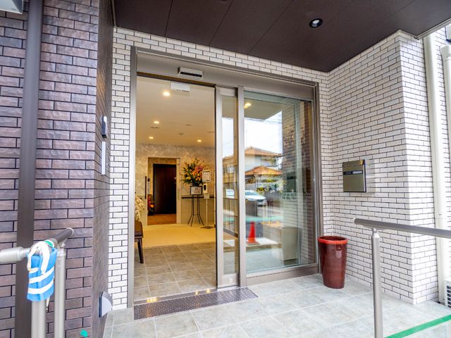 入口が広く明るいエントランス 玄関 広々とした入り口はバリアフリー設計で、誰もがスムーズに出入りできるようになっています。ここから新しい職場生活が始まります。