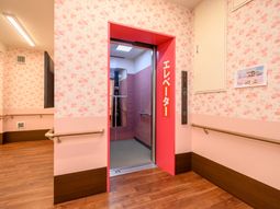 ピンクの壁紙のエレベーター前