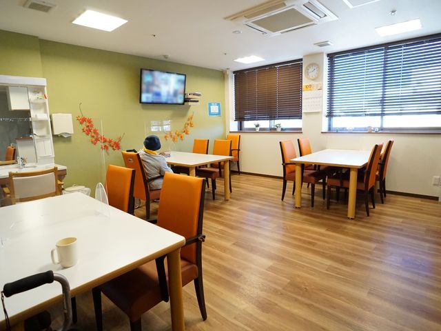 暖かい雰囲気の食堂 共有スペース 温かみのある照明と落ち着いた色合いの椅子が並ぶ食堂では、テレビを視聴しながらくつろげます。コミュニケーションの場としてもぴったりで、新しい仲間との出会いがあります。