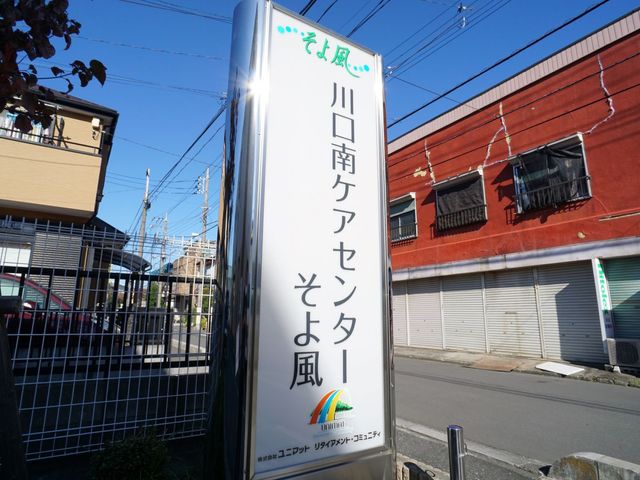 施設の看板 ロゴ 日差しの中、施設の入り口を示す明るく目立つ看板。この先に新たな職場が待っています。