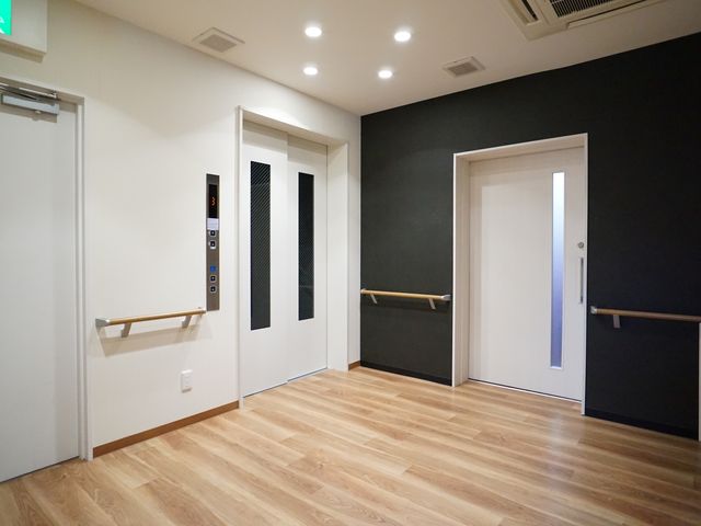 廊下とエレベーター エレベーター 明るくて清潔感のある廊下が広がっており、壁に設置された手すりが安全な歩行をサポートしています。
