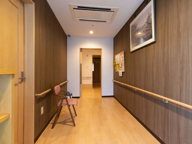 廊下に手すりと椅子 通路 手を頼りに歩けるよう手すりが設置された廊下です。持ち運び可能な椅子も用意されており、休憩しながら移動ができます。