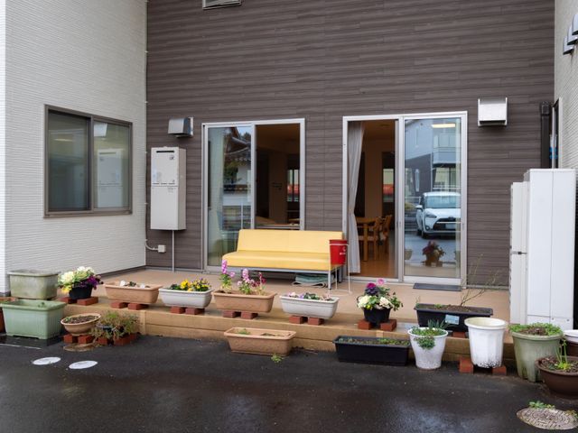入り口と花壇の景色 ベランダ ウェルカムな雰囲気を醸し出すエントランスで、様々な植物が訪れる人を優しく迎えています。