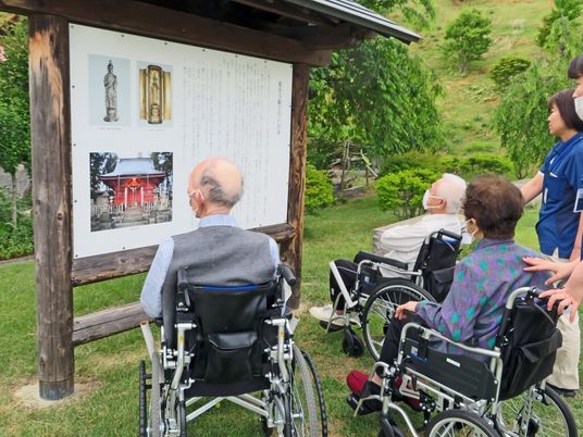 車椅子の方々が野外で看板を見る
