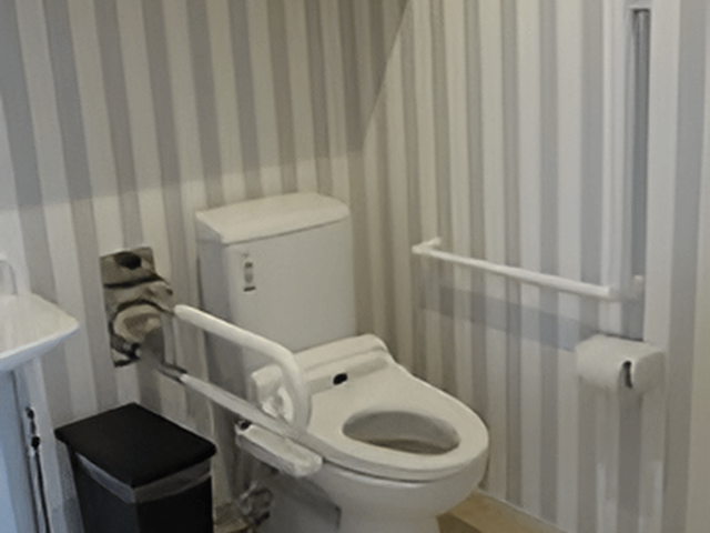 バリアフリートイレ設備 トイレ 手すり付きの清潔なトイレ空間です。利用者の安全と快適さを考慮した配慮がされています。