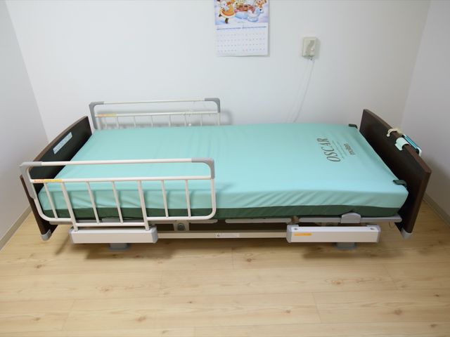 機能的な居室のベッド ベッド 安全な手すりがついた清潔なベッドが配備された居室です。働く際には、利用者様の快適な日々をサポートする環境が整っています。
