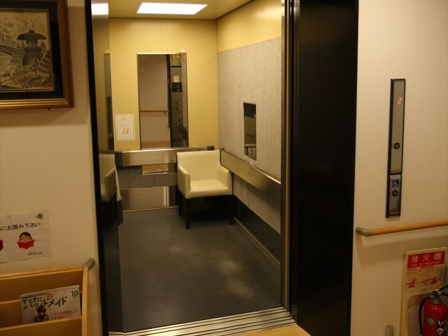 エレベーター前の入口 エレベーター ゆとりある空間のエントランスは、利便性を考えた広々とした設計です。明るい照明が印象的で、出入りがスムーズに行えます。