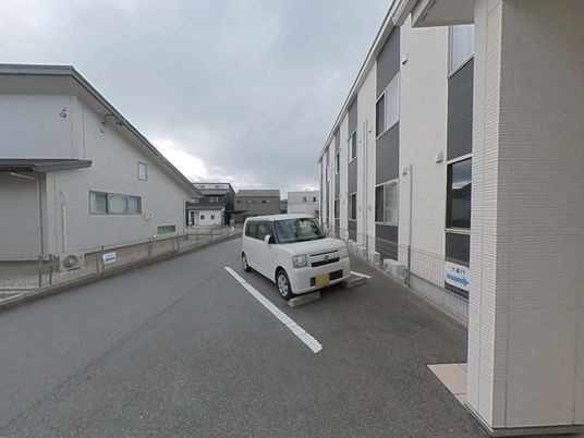 白い壁の建物と駐車場