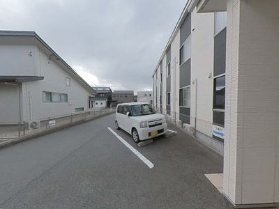 白い壁の建物と駐車場
