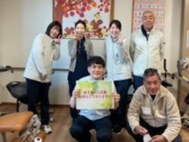 利用者と職員の集合シーン リビング 利用者の方と職員の皆さんが並び、明るく和やかな雰囲気が伝わります。就業時のチームの様子をイメージしやすい場面です。