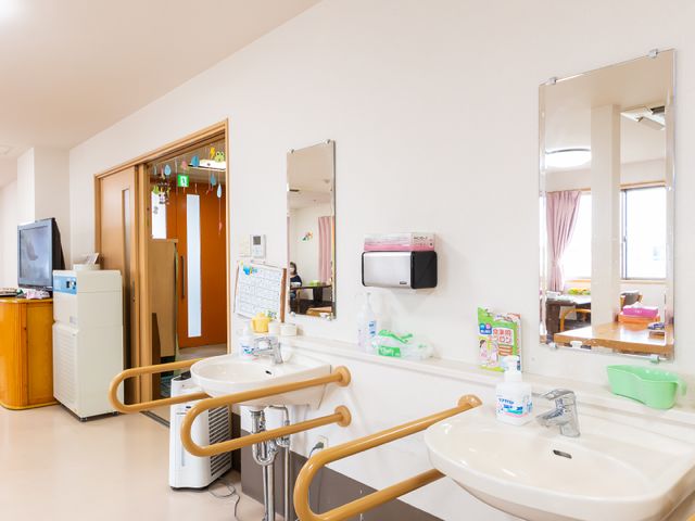 洗面所と共有スペース 洗面台 手すりがついた洗面台は、安全にご使用いただける設計です。周辺にはリラックスできる共有スペースも整っています。