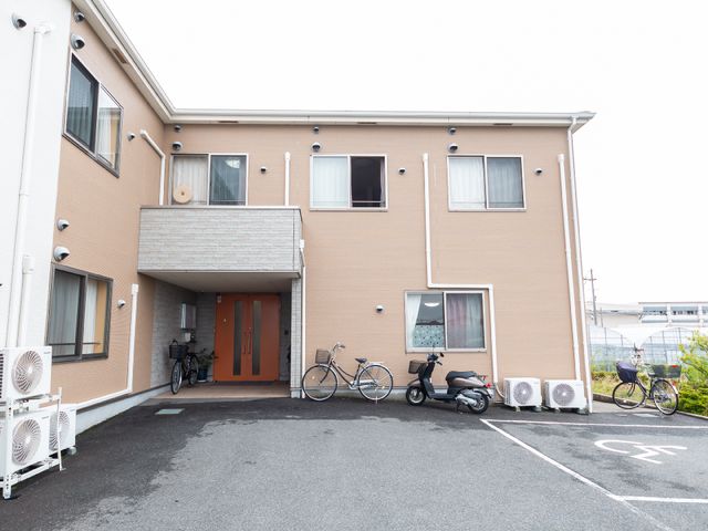 茶色の建物のエントランス 外観 清潔感のあるエントランスは、来訪者を温かく迎えてくれます。手入れされたスペースで明るい出迎えが期待できそうです。
