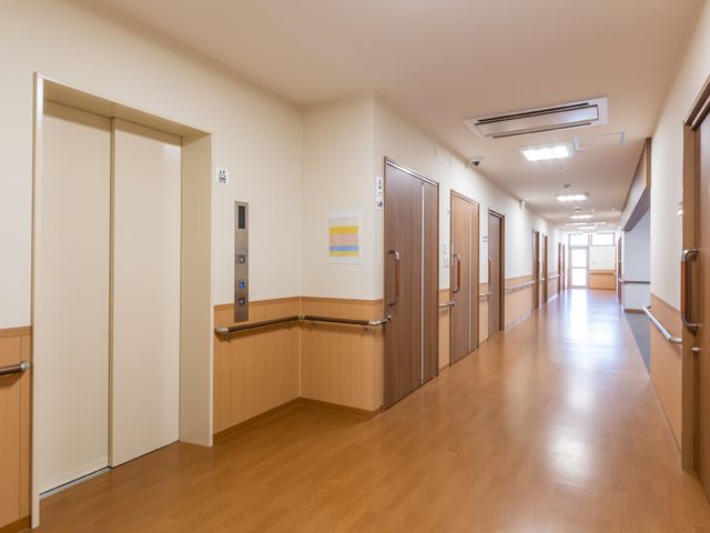 明るい廊下とエレベーター エレベーター 手すりの設置された清潔感あふれる廊下は、移動に便利な設計になっております。安心してご勤務いただける環境です。