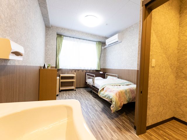 快適な個室の寝室 居室 広々とした居室は落ち着いた色合いで、個々の時間を大切にする環境が整っています。明るく柔らかな光が窓から射し込み、穏やかな雰囲気を演出しています。