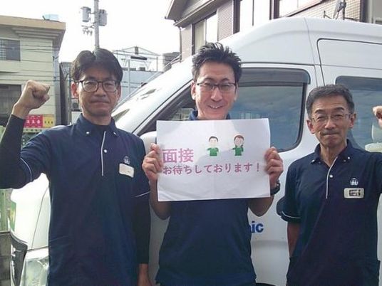 スタッフが看板を持つ外観  