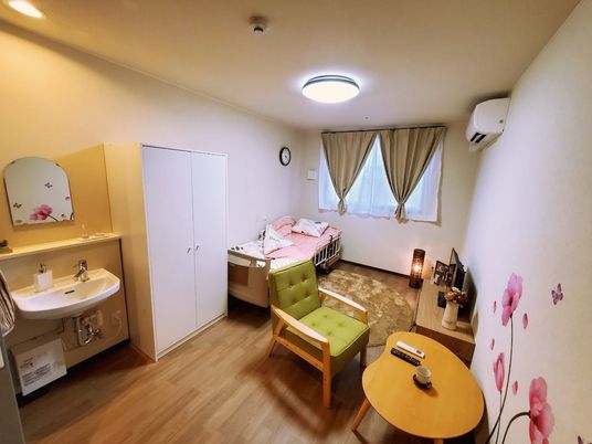 洗面台が備え付けられ、テレビやテーブル、収納などが配置された部屋