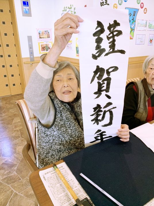 新年の書初めを行い、完成した作品を掲げて見せる入居者様