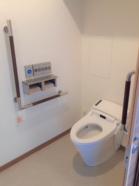 壁に手すりが付いたウォシュレット機能搭載の洋式トイレ