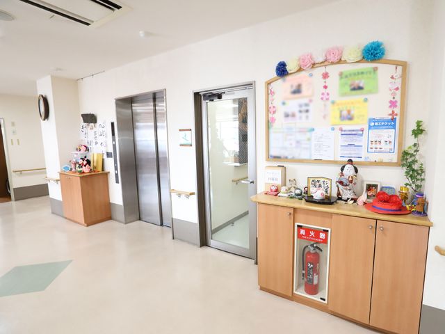 エレベーターと掲示板の廊下 共用スペース エレベーター横には季節感あふれる装飾がされ、暖かい雰囲気の廊下が広がっており、職員と利用者様のコミュニケーションの場となっています。