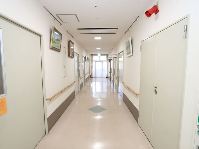 明るい廊下 廊下 手すり沿いの清潔で広々とした通路は、ご利用の方々の移動を安全にサポートします。壁に掛けられた絵画が温かみを添えています。